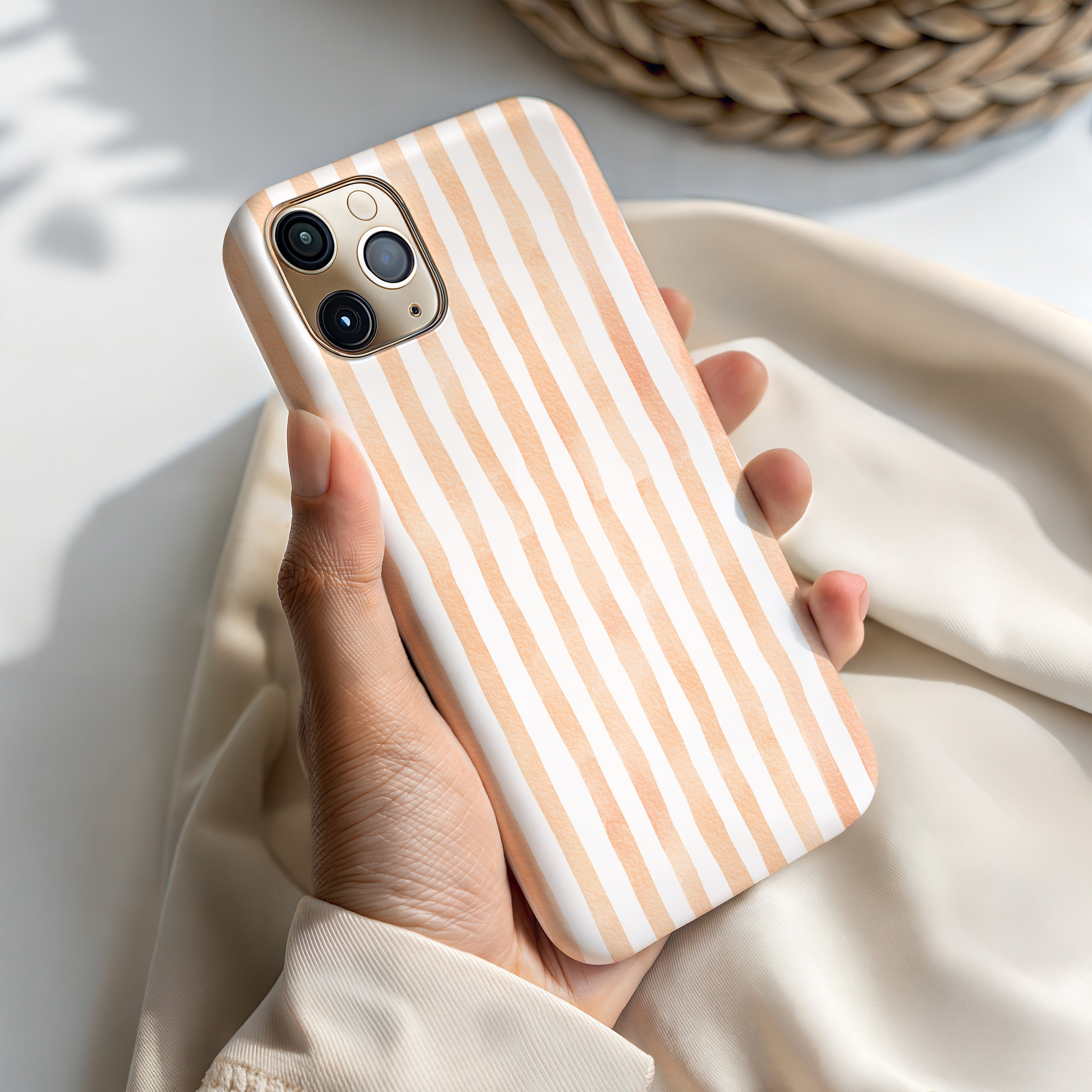 A hand holding a white and orange striped phone case.
