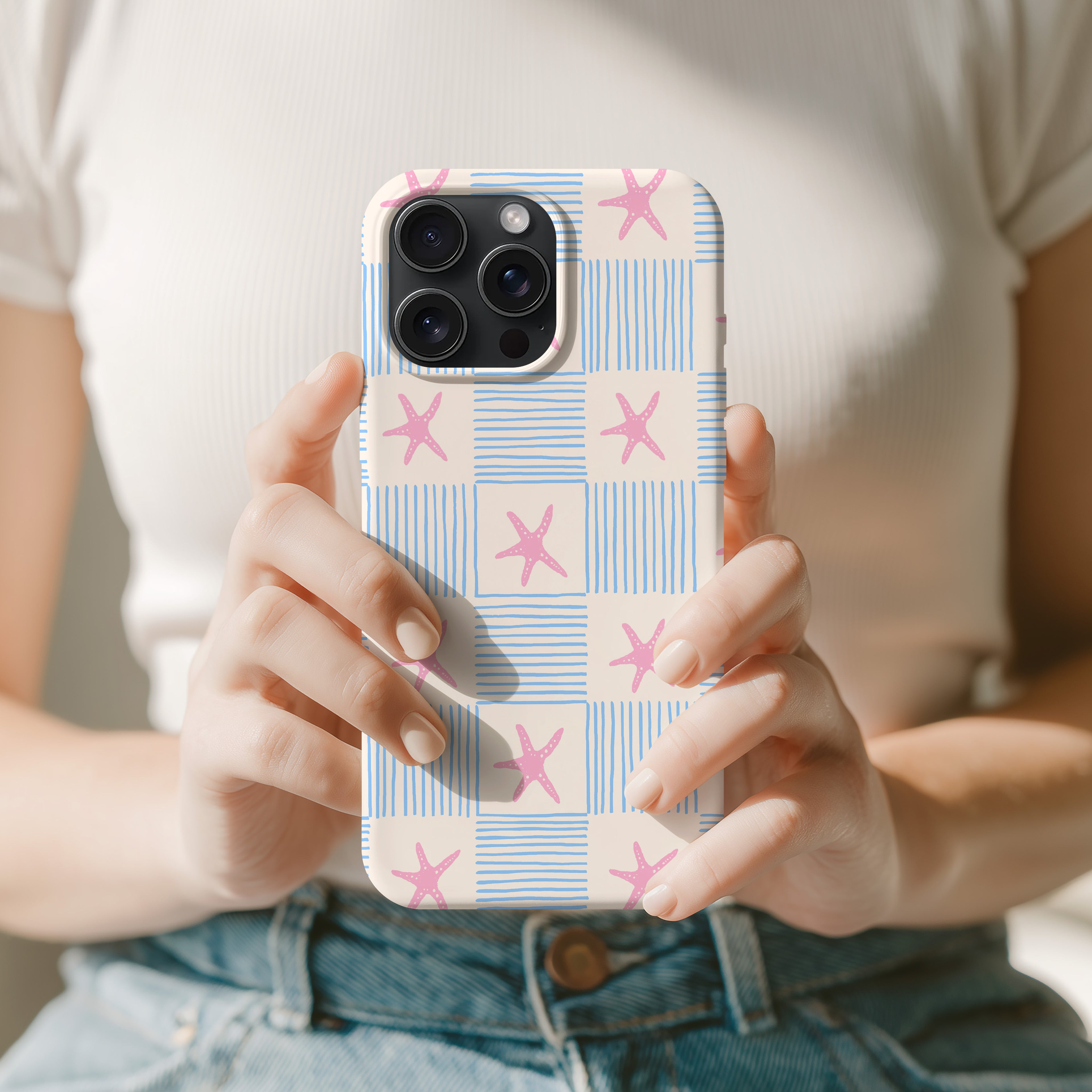 A person is holding a phone with a patterned case featuring pink and blue stars.
