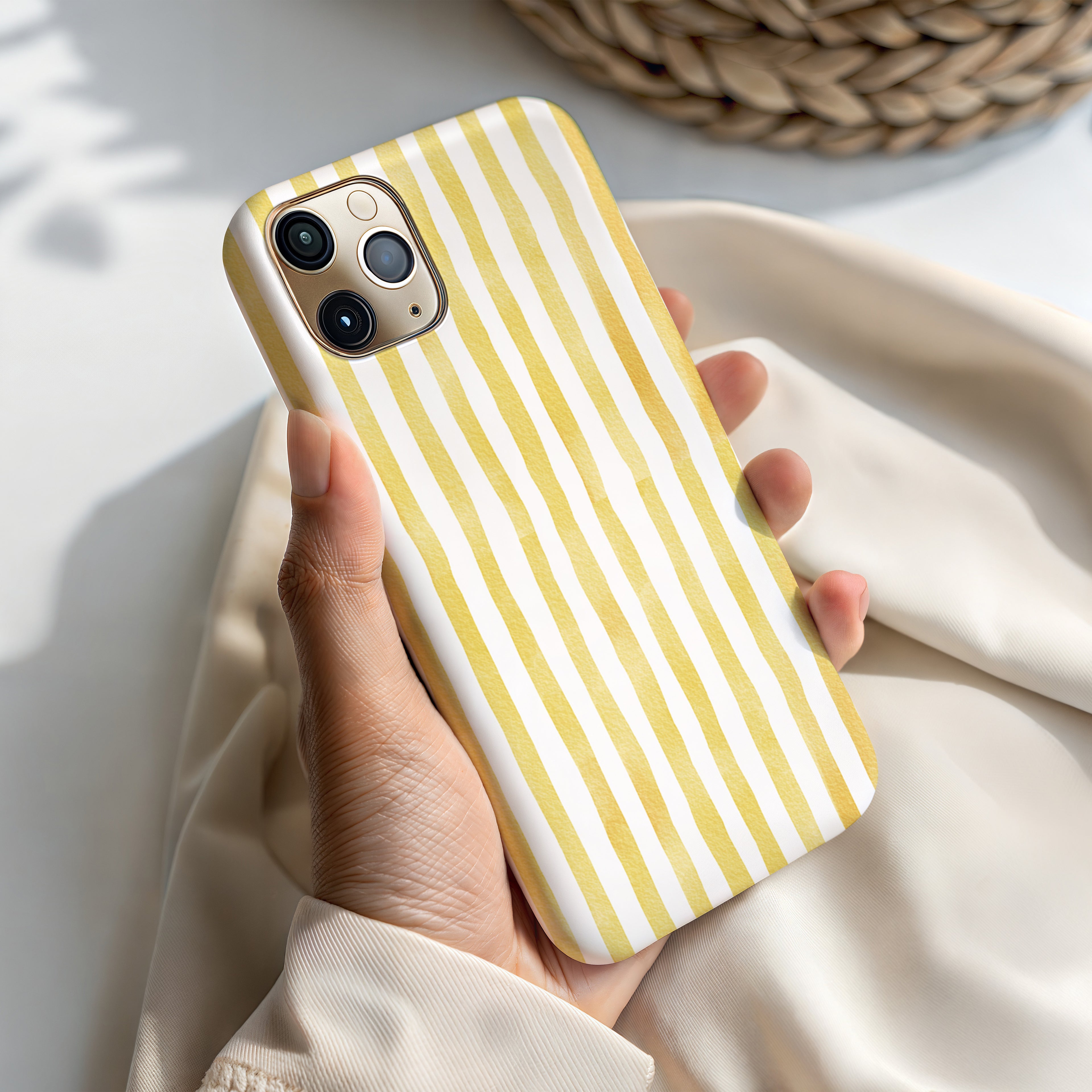 A person's hand holding a yellow and white striped phone case.