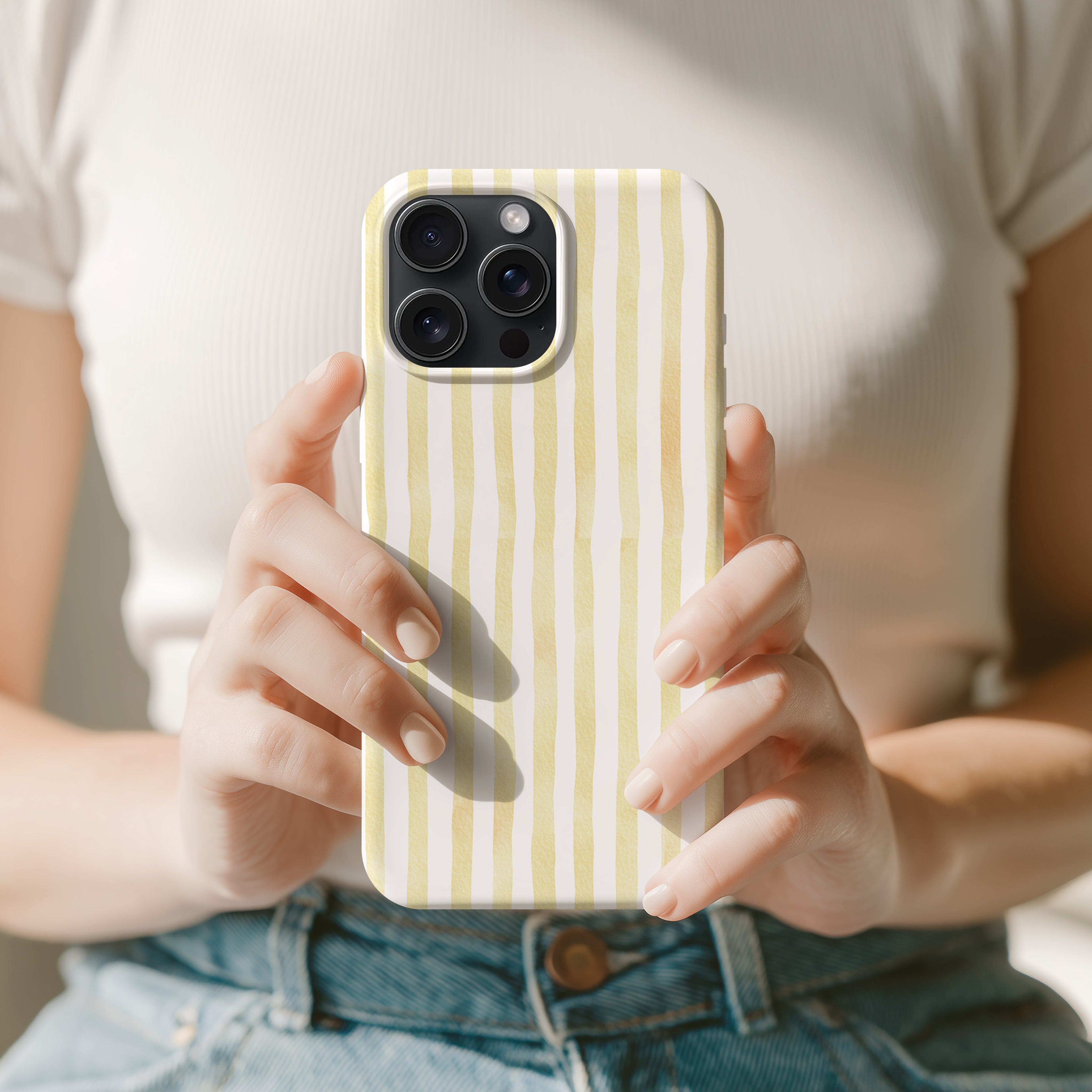 A person is holding a yellow and white striped phone case in their hands.