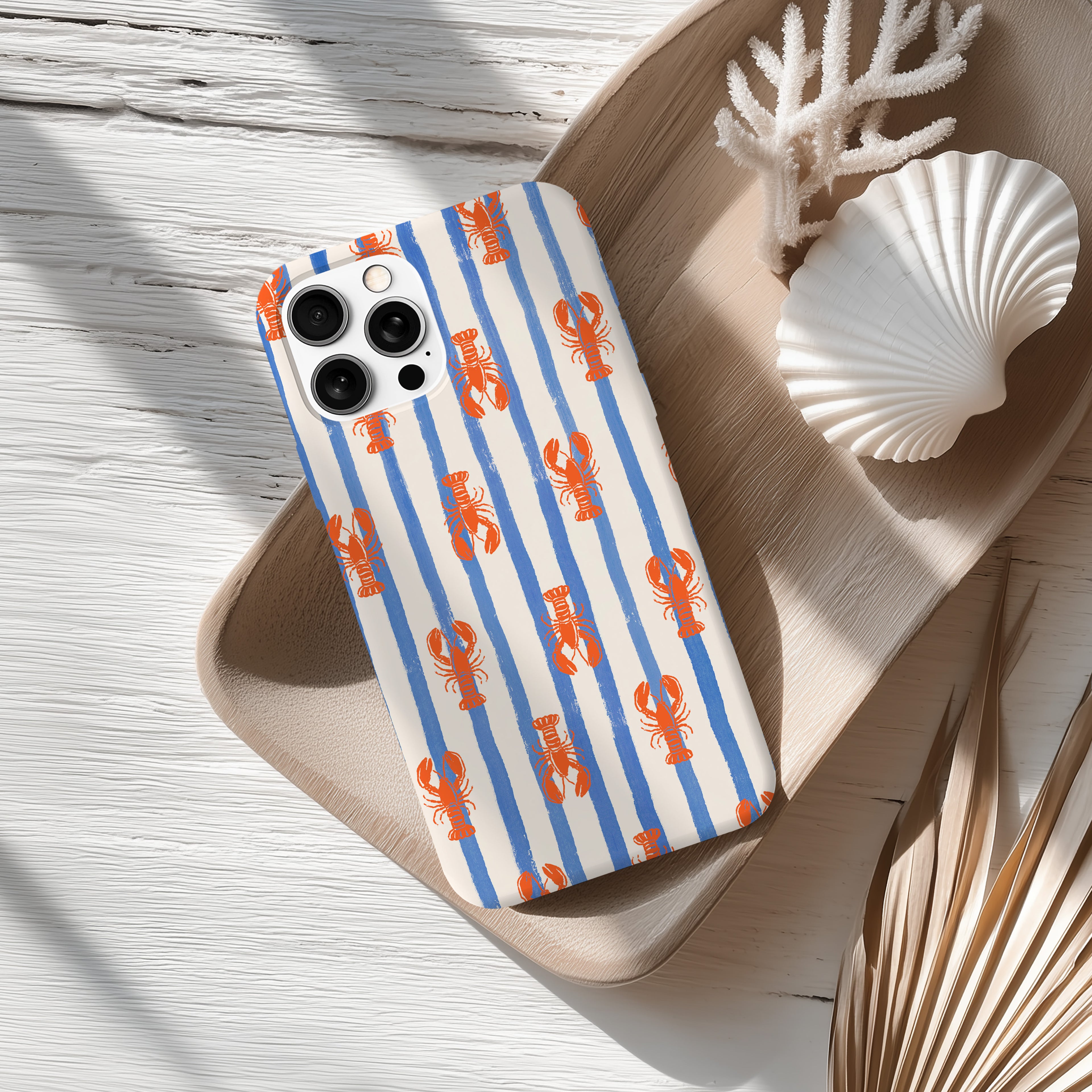 a smartphone case with a striped pattern of blue and orange lines, along with a seashell and some dried leaves on a wooden surface.