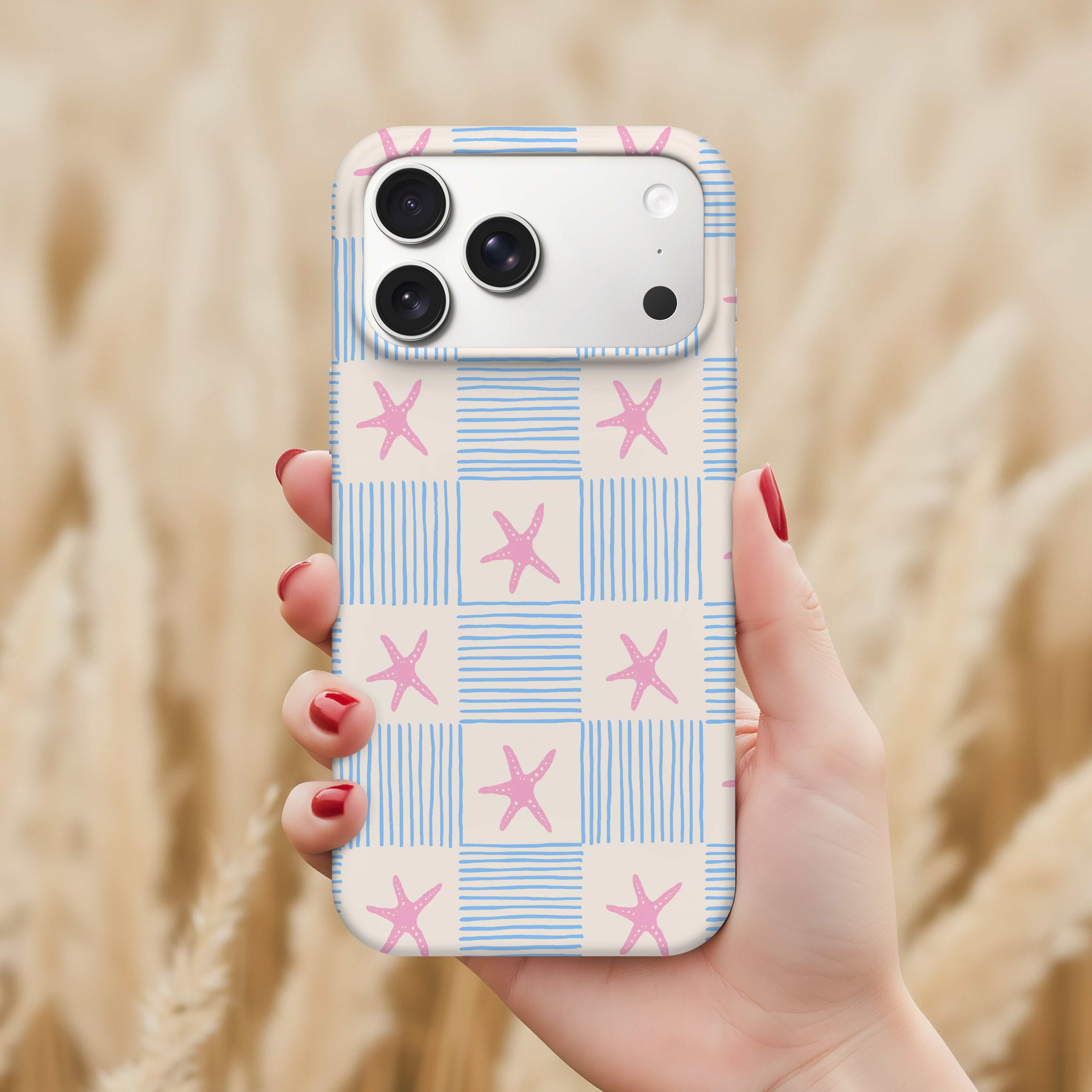 A hand holding a smartphone with a patterned case featuring blue and white stripes and pink star shapes.