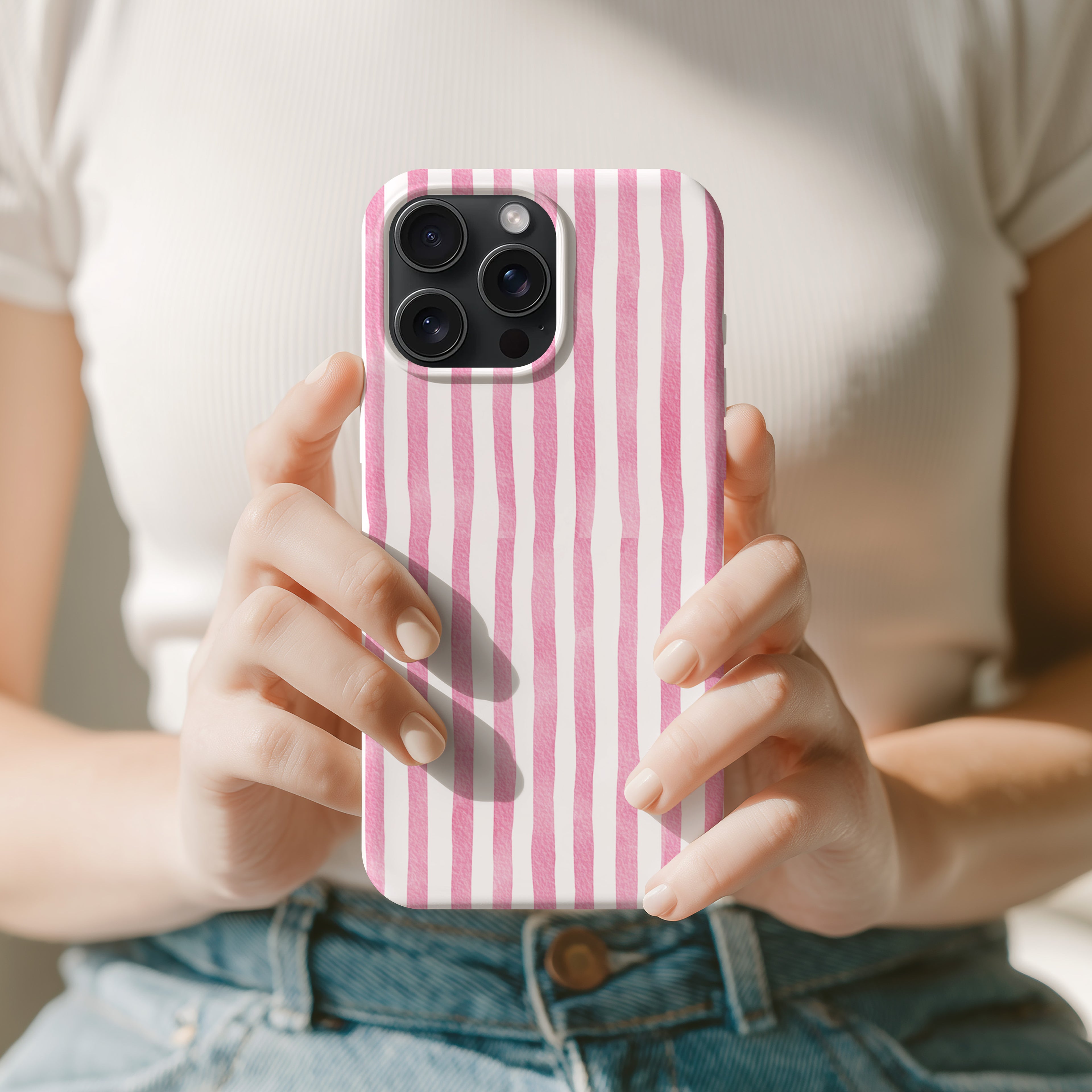 A person is holding a pink and white striped phone case in their hands.