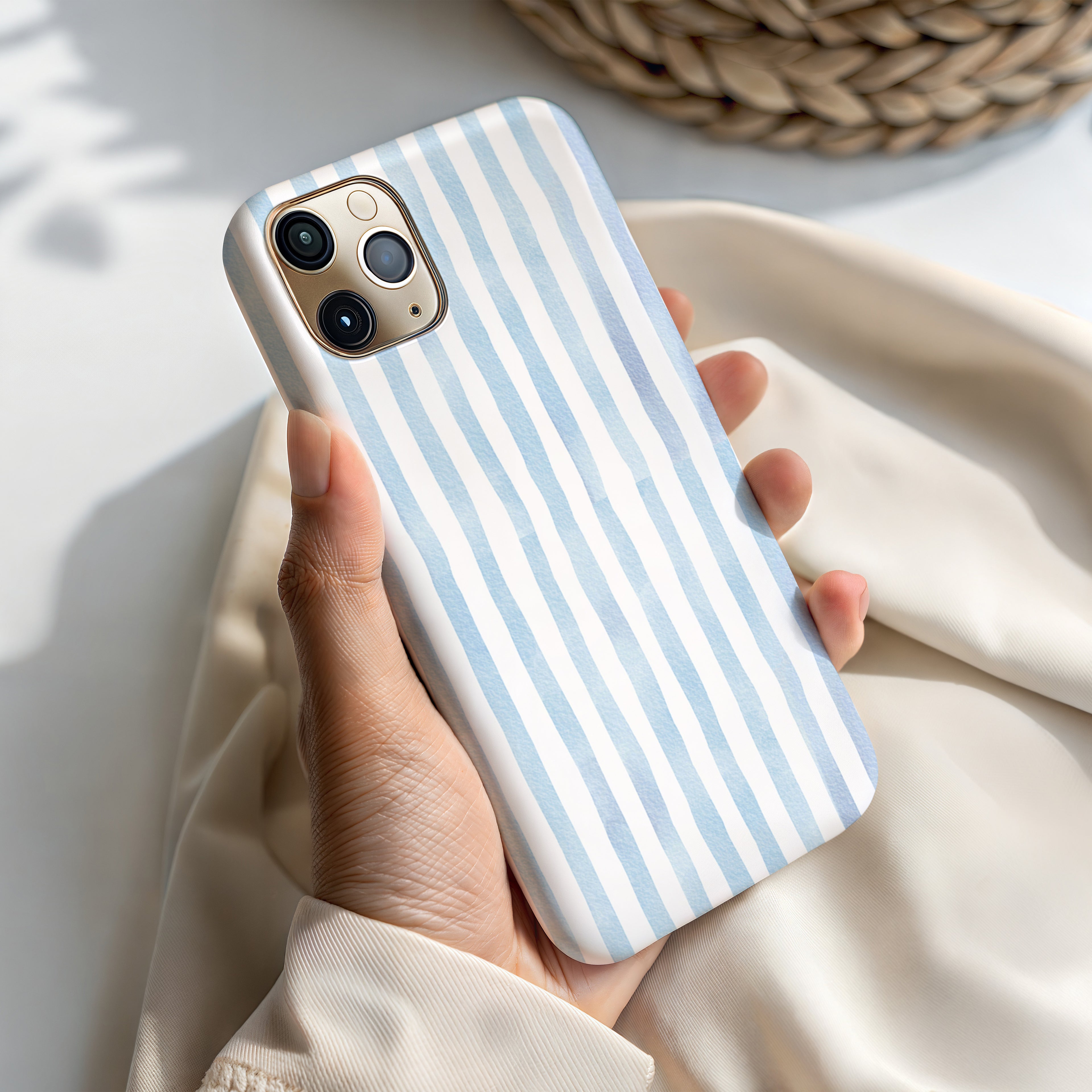 A hand holding a white and blue striped phone case.