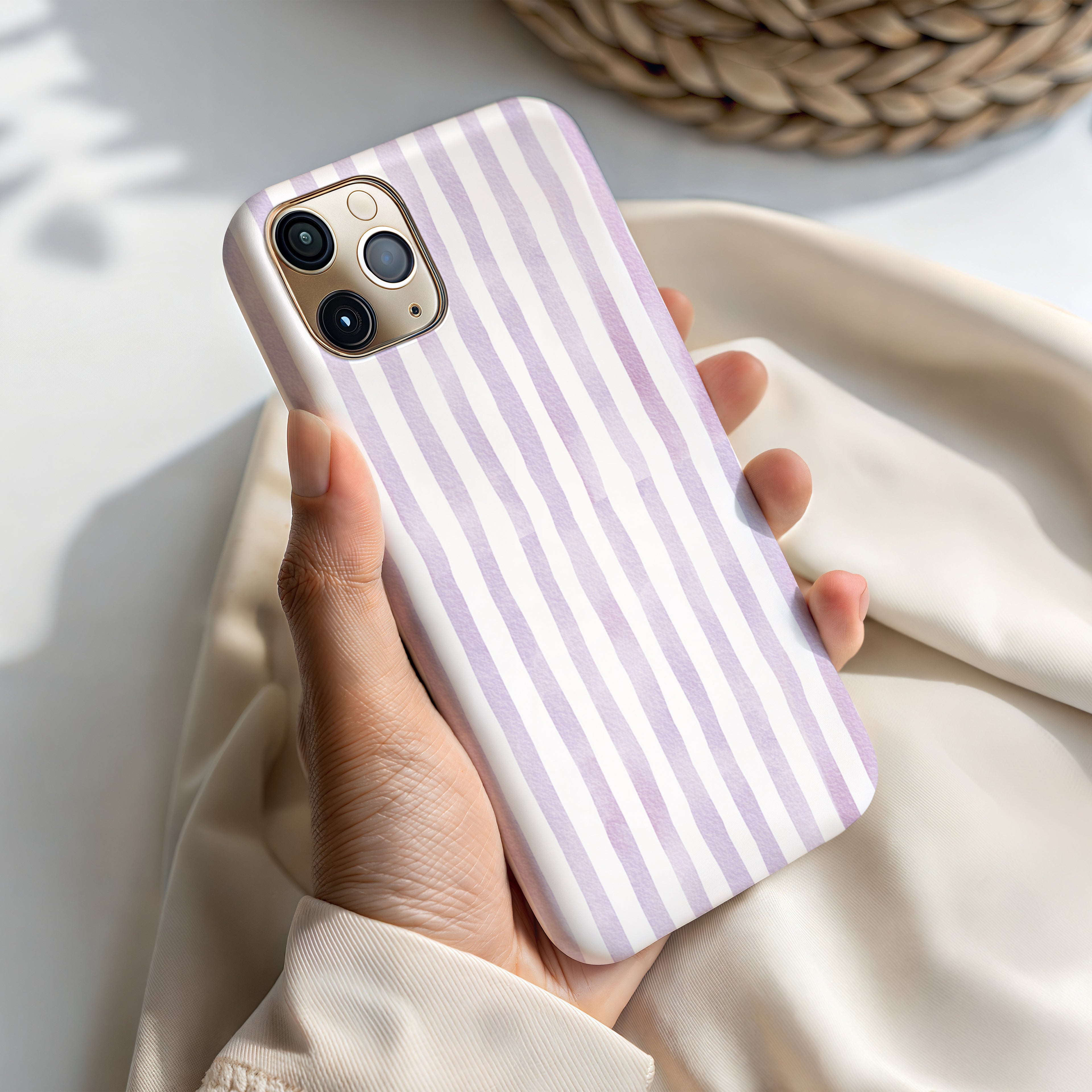 A hand holding a white and purple striped phone case.