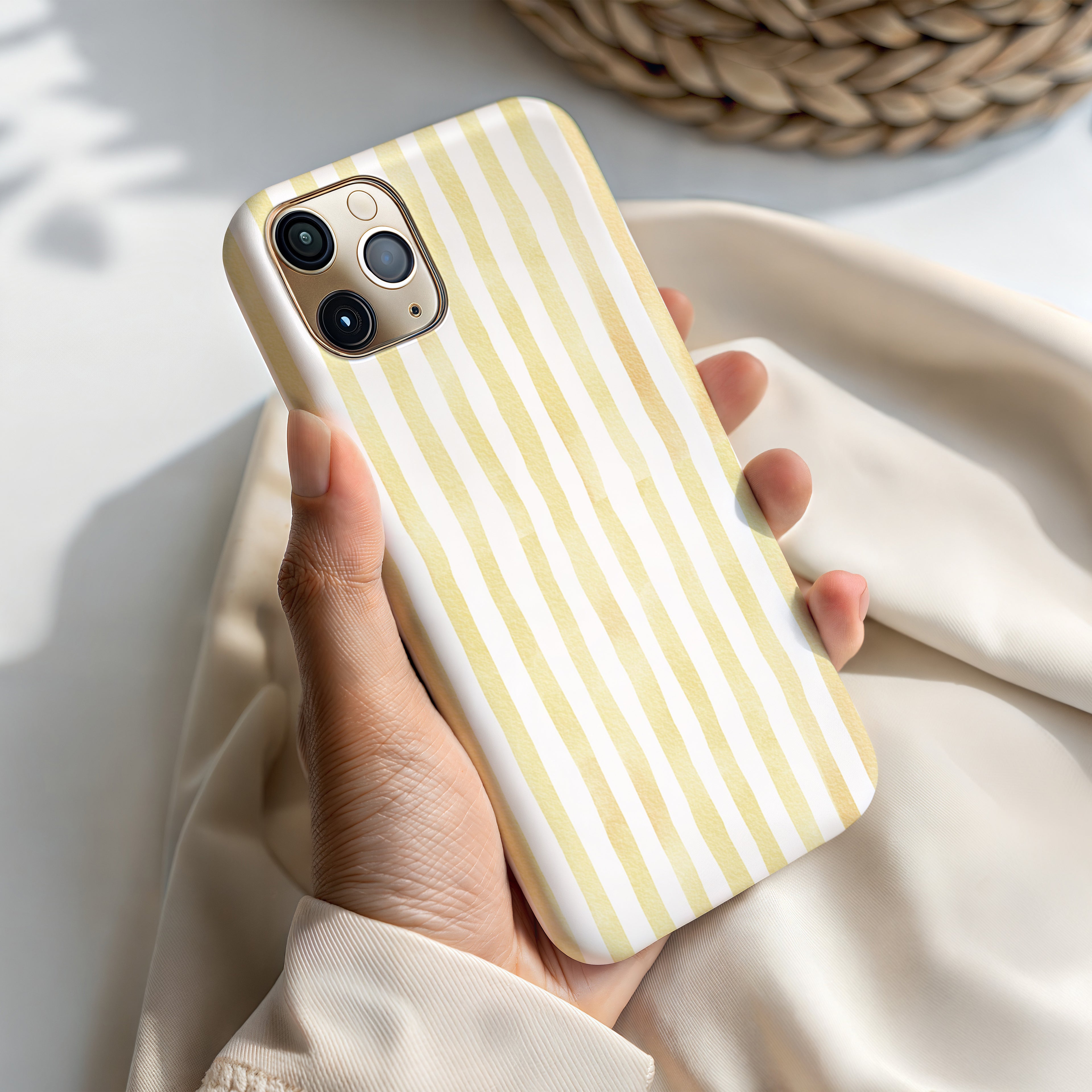 A person's hand holding a yellow and white striped phone case.