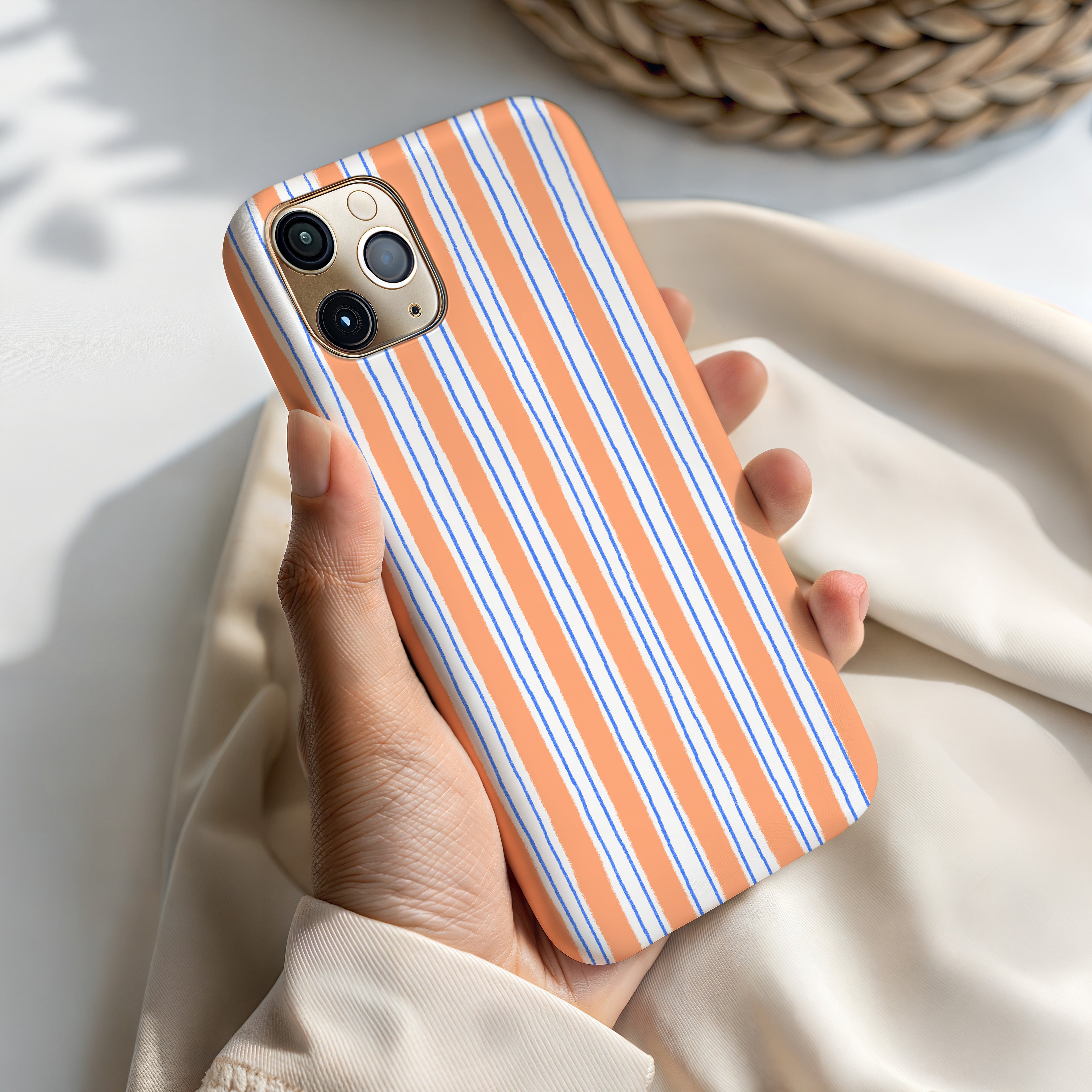 A person's hand holding a phone with a striped orange and white case.