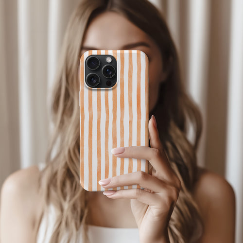 A woman with long, wavy hair is holding up a striped phone case with orange and white stripes.