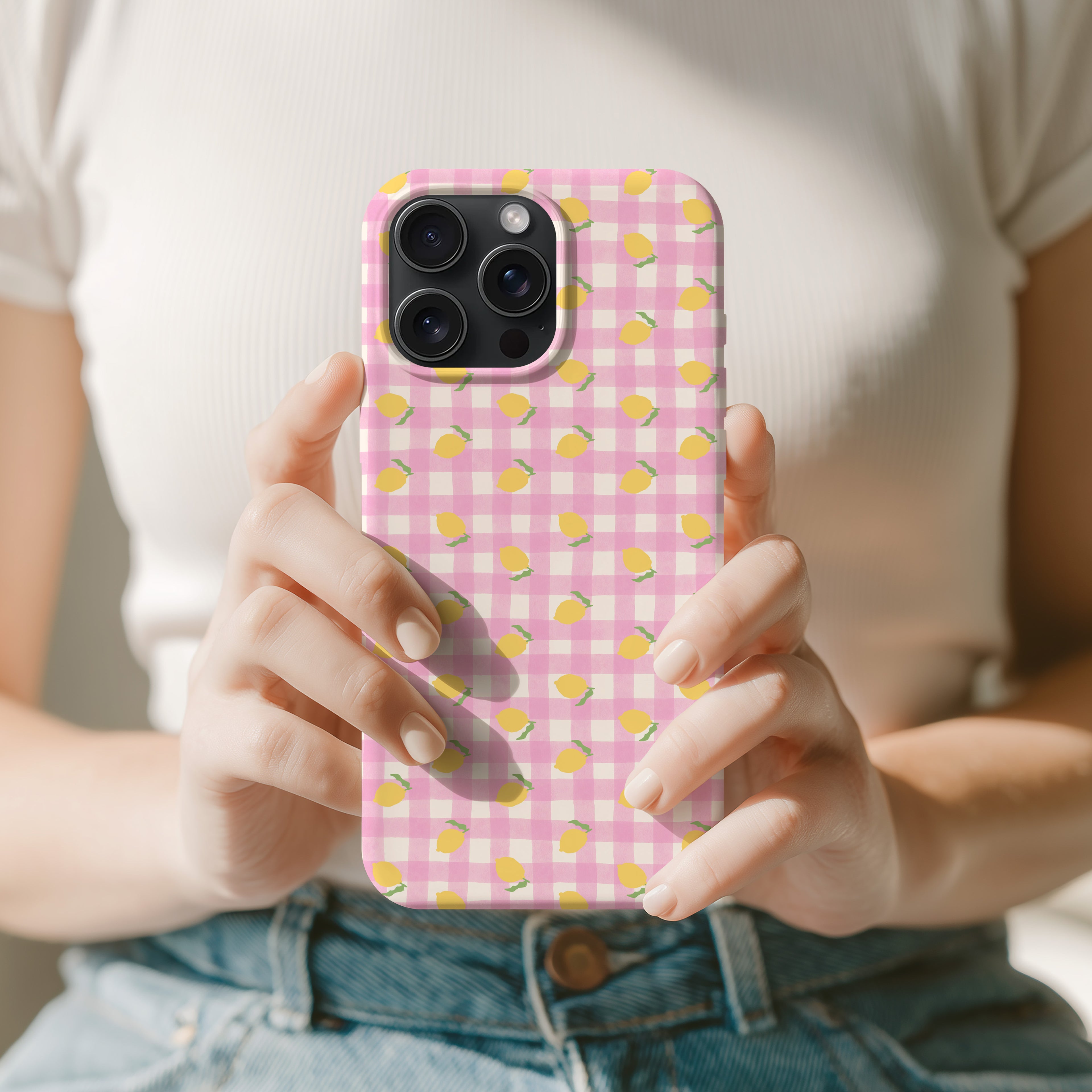 A person is holding a phone case with a pink and yellow checkered pattern.